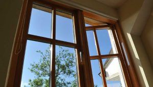 En esta foto se ve claramente una ventana de madera hecha a medida con una estructura de aluminio